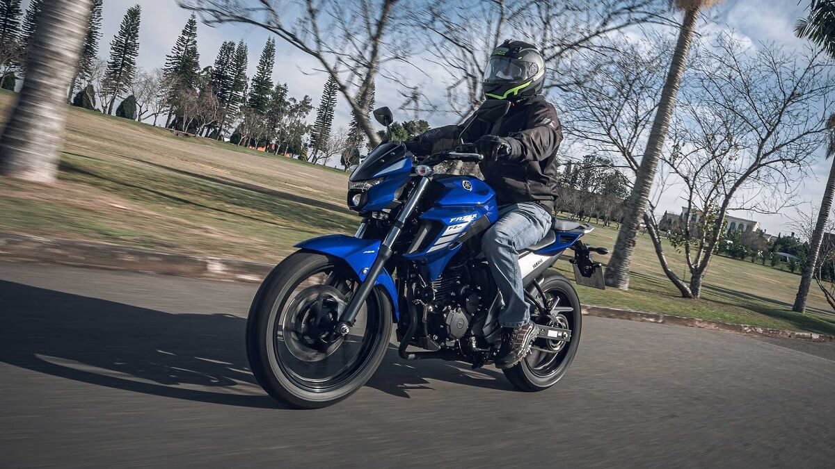 Foto lateral de uma pessoa andando em uma Yamaha 250 Fazer 2023 azul