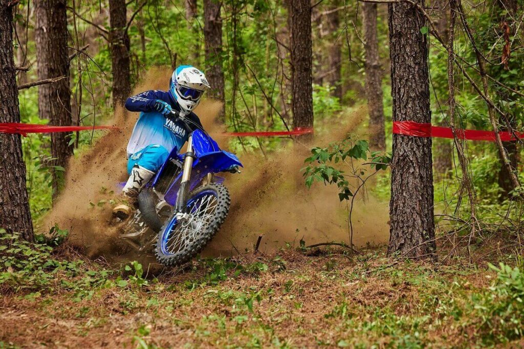 YZ 250 2023 azul andando em uma trilha no meio do mato