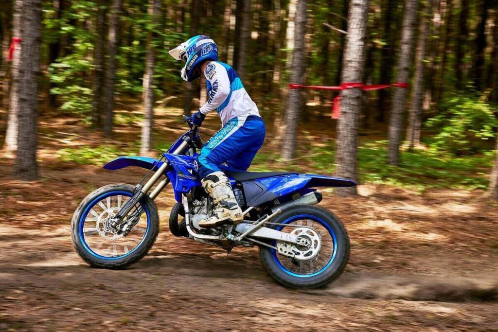 Foto de uma pessoa andando com uma YZ 250 2023 em uma trilha