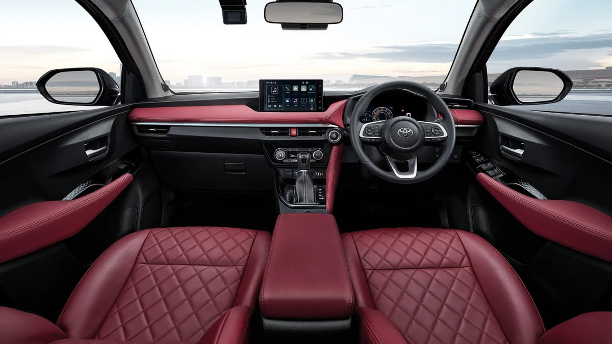 Toyota Yaris interior com couro vermelho, a foto também mostra a tela multimídia volante e o retrovisor.