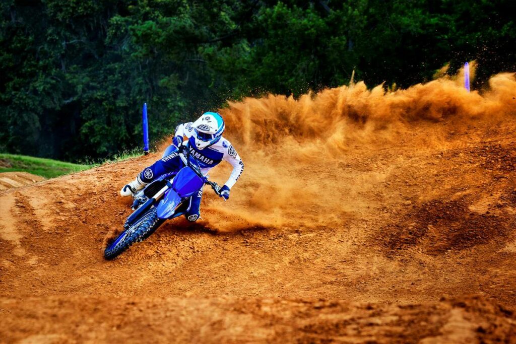 Foto de um piloto fazendo uma curva em um paredão com uma YZ 450 F 2023 azul