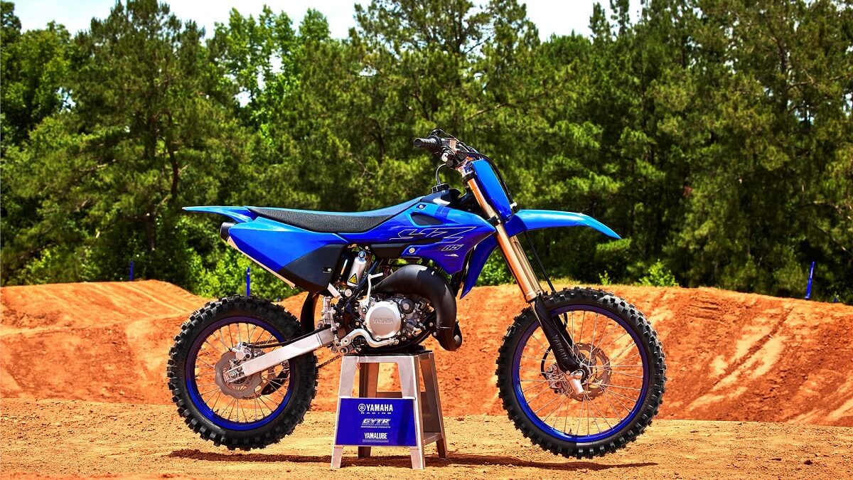 Foto lateral de uma YZ 85 LW 2023 azul, a moto esta sob um cavalete de exposição