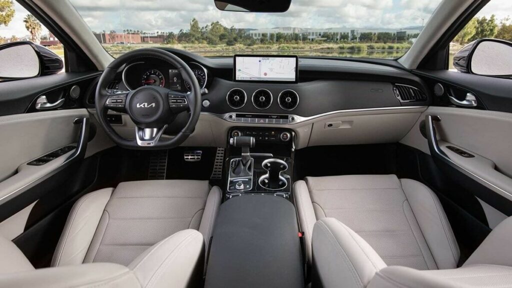 Foto do interior do Stinger 2023, com bancos brancos e um painel bem grande