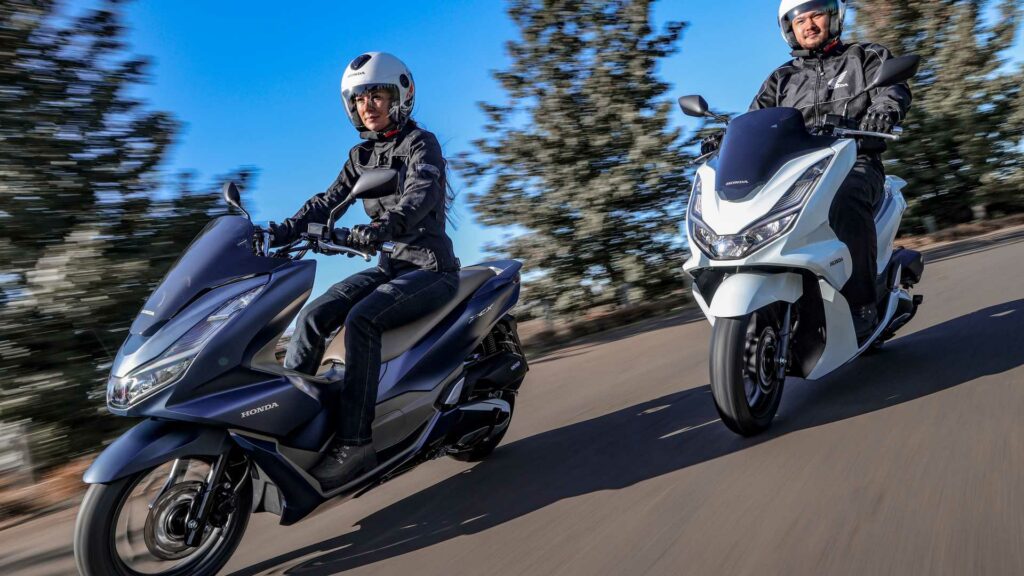 Foto de duas pessoas andando com uma Honda PCX 160 2023