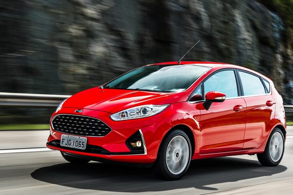 Foto frontal de um Ford Fiesta em 2023 vermelho andando em uma estrada