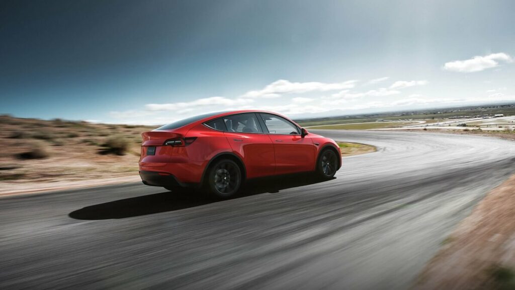 Foto de um Tesla Model Y 2023 vermelho andando na estrada