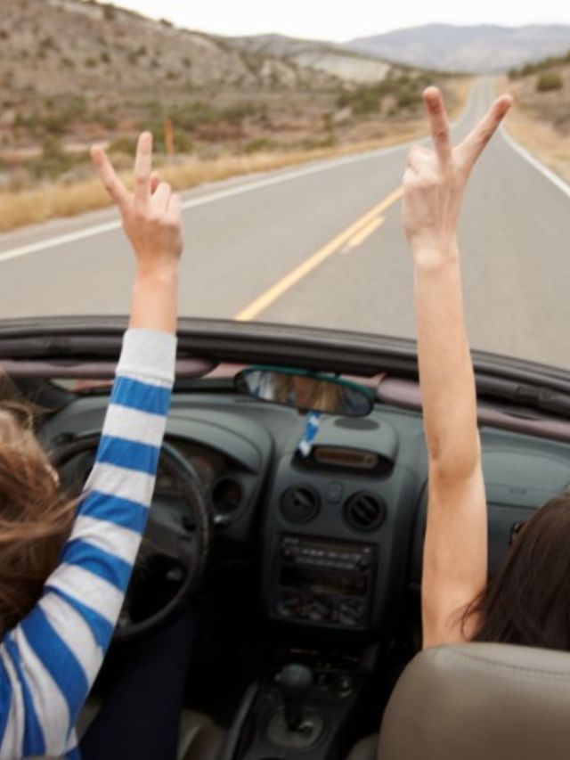 Duas mulheres levantando as mãos enquanto estão no carro