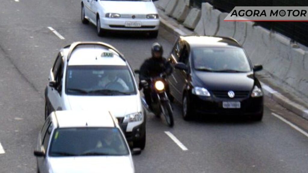 Motoqueiro passando pelo meio dos carros.
