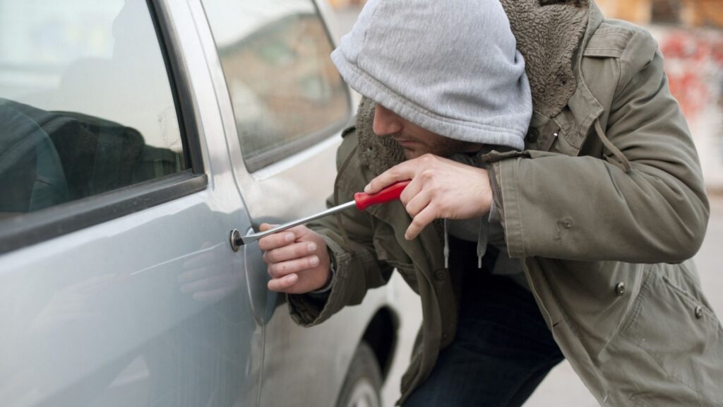 Homem roubando carro com chave de fenda