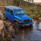Jeep Wrangler azul passando na água.