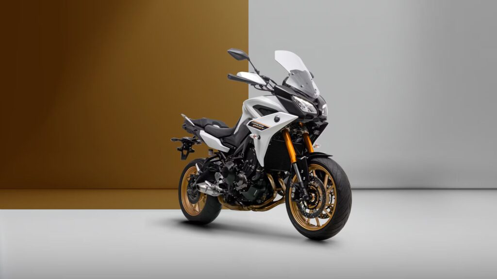 Yamaha Tracer 900 GT 2025 branca com dourado em fundo branco com marrom.