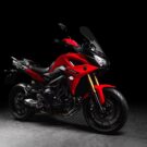 Yamaha Tracer 900 GT 2025 vermelha em fundo escuro.