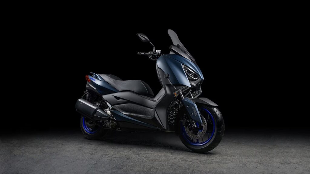 Yamaha XMAX ABS 2025 em fundo preto na diagonal.