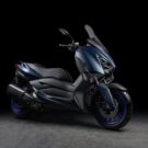 Yamaha XMAX ABS 2025 em fundo preto na diagonal.