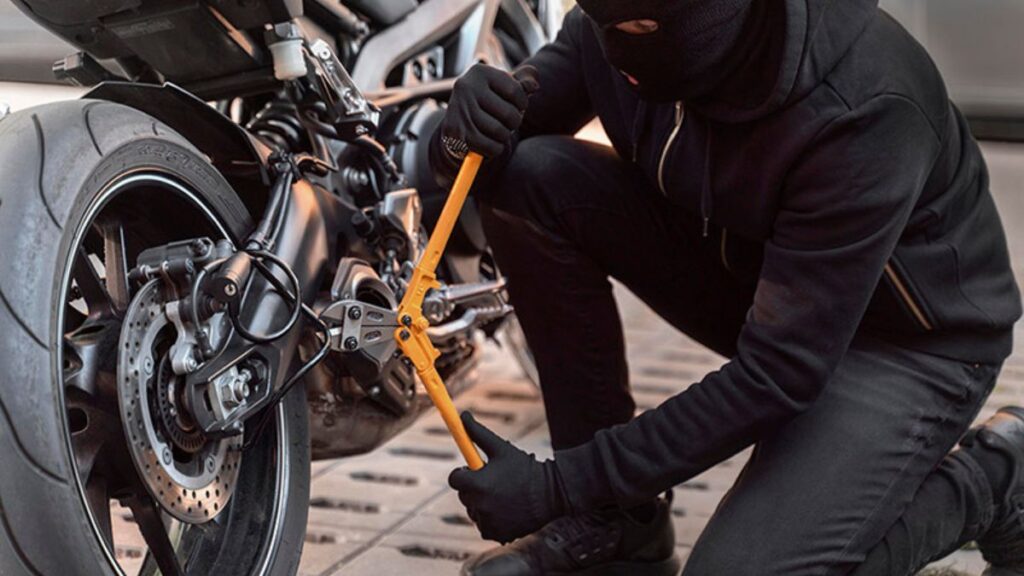 Homem roubando moto cortando corrente na roda.