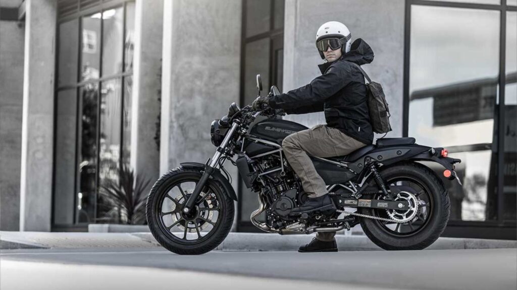 Lateral da Kawasaki Eliminator 500 2025 com homem em cima parado.