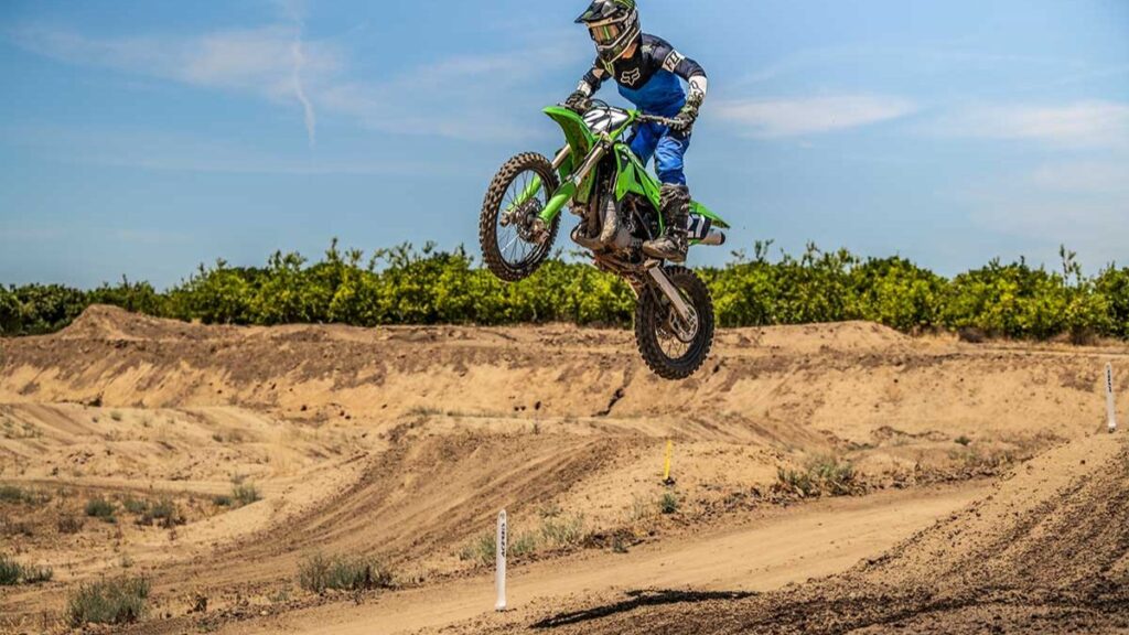 Kawasaki KX112 2025 pulando em rampa na pista de motocross.
