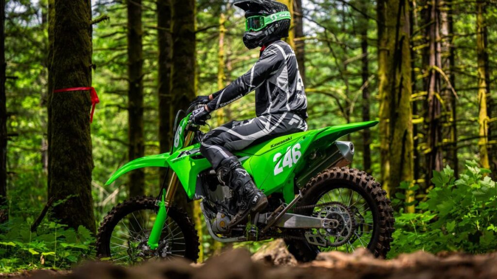 Lateral da Kawasaki KX250X 2025 verde em floresta.