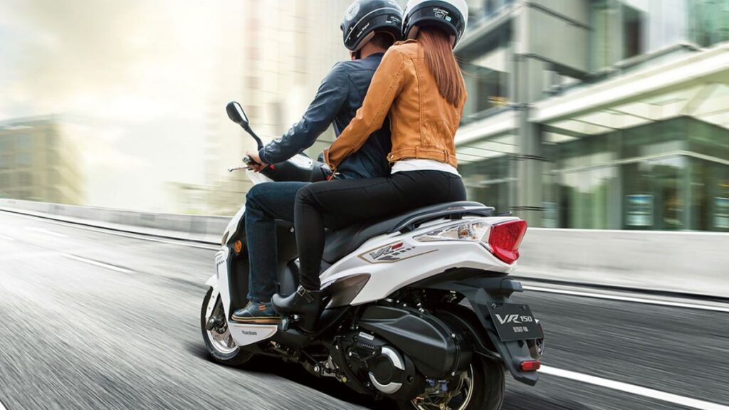 Traseira da Haojue VR150 2025 branca em movimento com passageiro.