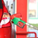 Carro vermelho abastecendo em posto.