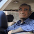 Idoso olhando para a janela do carro.