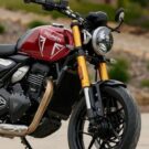 Uma moto Triumph vermelha parada na diagonal.