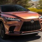 Um carro híbrido laranja da Lexus em velocidade.