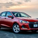 Carro Chevrolet Onix Turbo vermelho parado na diagonal.