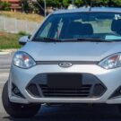 Um Ford Fiesta Sedan prata parado na diagonal.