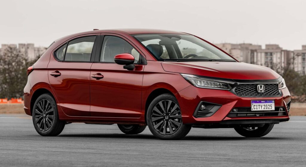 Honda City vermelho parado de lado.