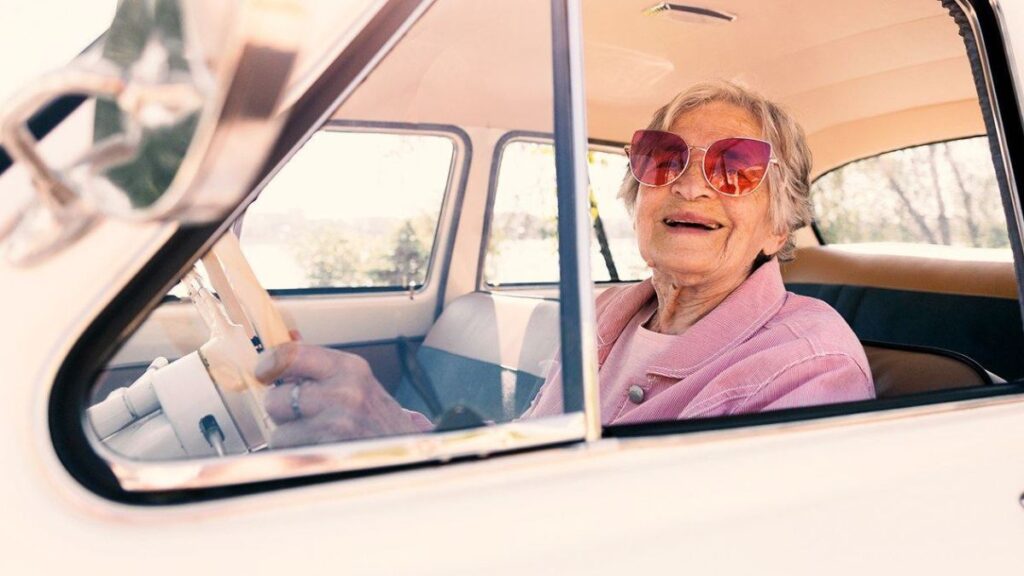 Idosa em carro antigo.