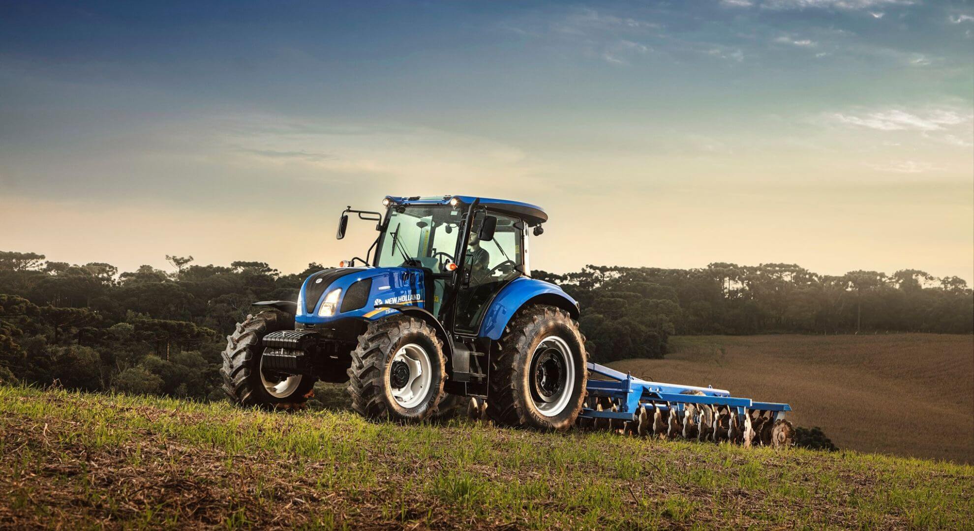 Trator New Holland azul parado na diagonal.
