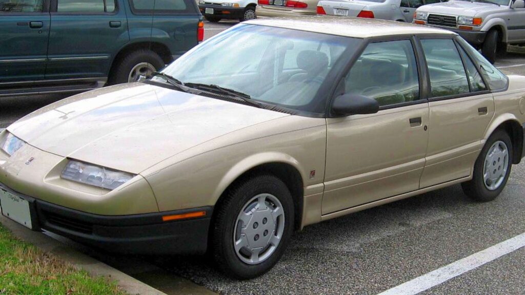 Chevrolet Saturn bege estacionado em um estacionamento.