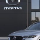 Carro prata da Mazda parado na frente da loja.