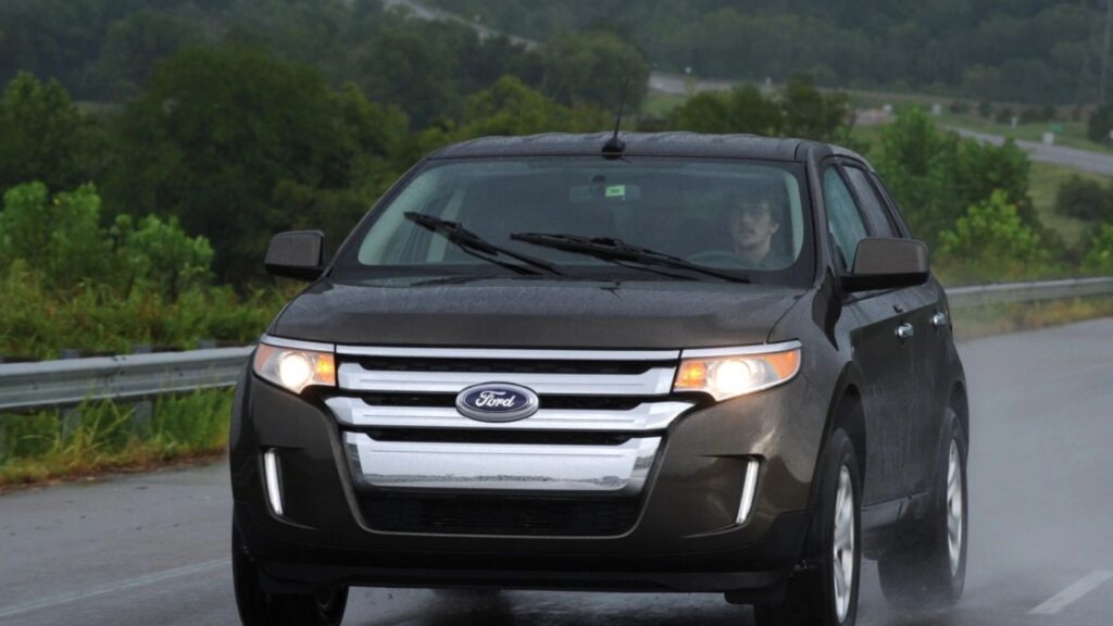 Ford Edge marrom andando na estrada na chuva.
