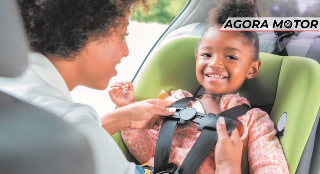 Mãe colocando sua filha na cadeirinha.