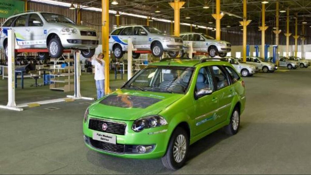 palio weekend eletrico verde em um galpão cheio de carros