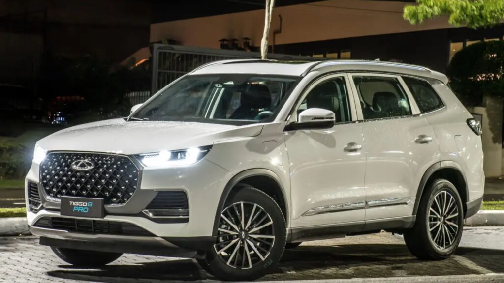 Tiggo 8 Pro PHEV branco na diagonal com os faróis ligados.