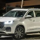 Tiggo 8 Pro PHEV branco na diagonal com os faróis ligados.