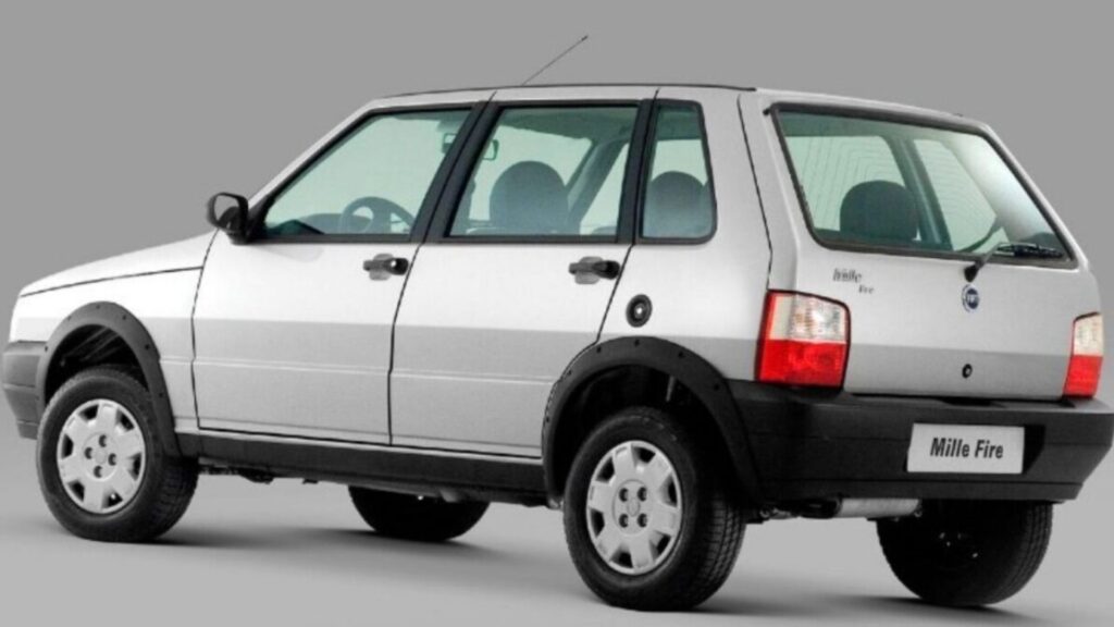 Fiat Uno prata na diagonal em um fundo cinza.