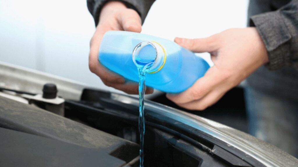 Anticongelante azul sendo colocado no radiador de carro.
