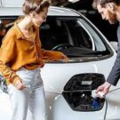 Homem de cinza explicando sobre um carro elétrico para a moça.