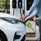 Homem carregando seu carro elétrico branco.