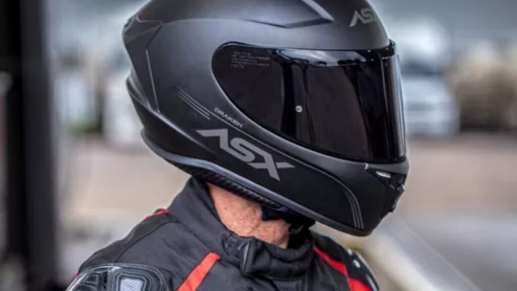 Motociclista com capacete preto e viseira fume.