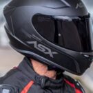 Motociclista com capacete preto e viseira fume.