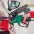 Pessoa abastecendo o carro com uma pisto de combustível verde.