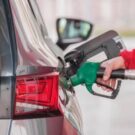 Pessoa abastecendo o carro com uma pisto de combustível verde.