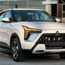 Mitsubishi Xforce HEV branco parado na diagonal com os faróis ligados.