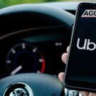 Motorista segurando celular com logo da Uber.