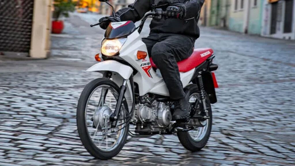 Honda Pop 110i branca fazendo uma curva.